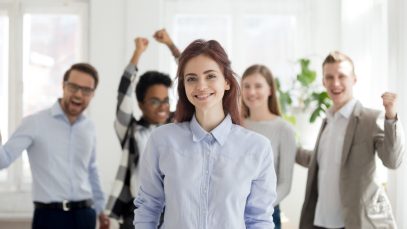 Portrait of successful female employee with excited colleagues a